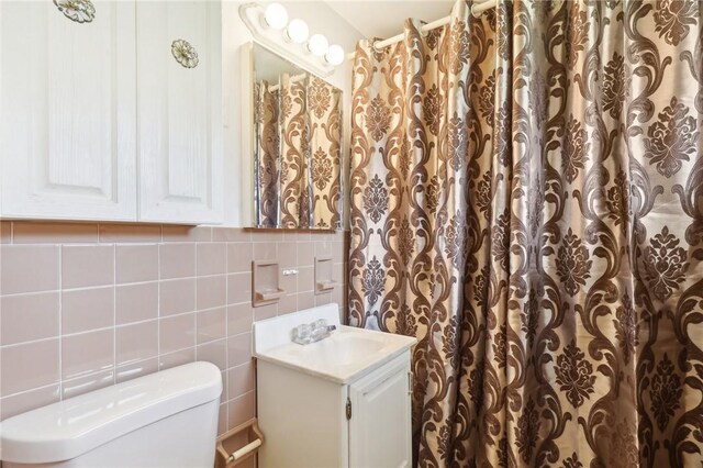 bathroom with vanity, toilet, and tile walls