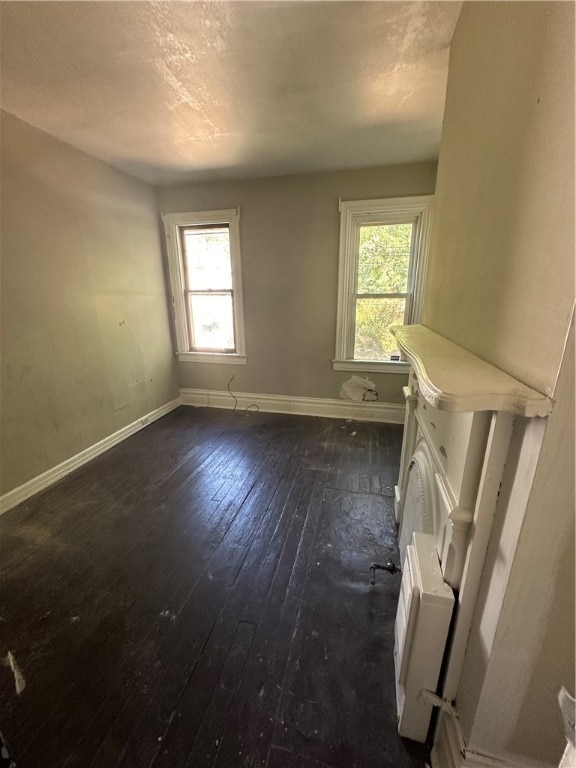 empty room with dark hardwood / wood-style flooring and a healthy amount of sunlight