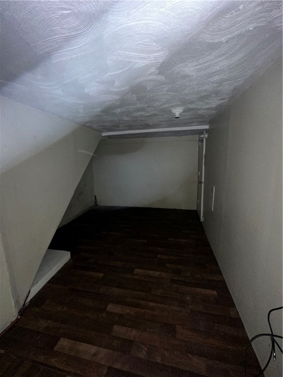 additional living space featuring dark wood-type flooring and vaulted ceiling