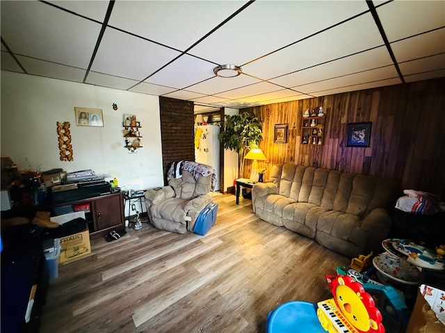 living room with a paneled ceiling, wooden walls, and hardwood / wood-style flooring