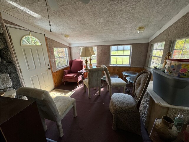 sitting room with lofted ceiling, a textured ceiling, and wooden walls