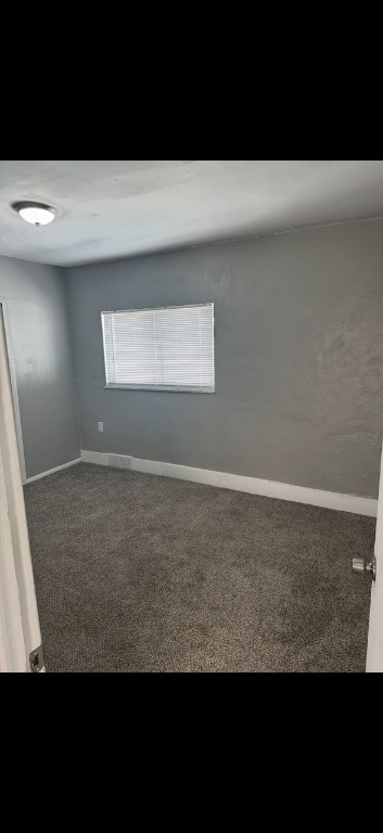 spare room featuring dark carpet