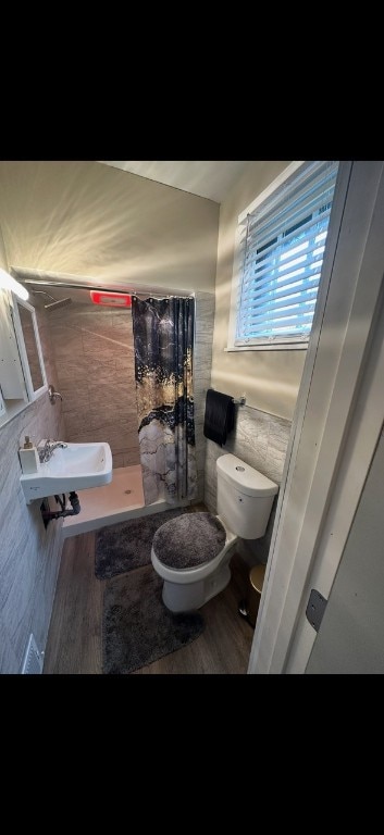 bathroom with a shower with shower curtain, toilet, sink, tile walls, and hardwood / wood-style flooring