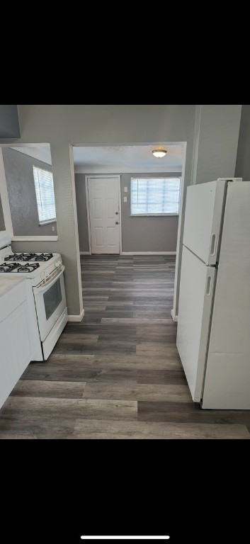 kitchen with dark hardwood / wood-style floors, white appliances, and white cabinetry