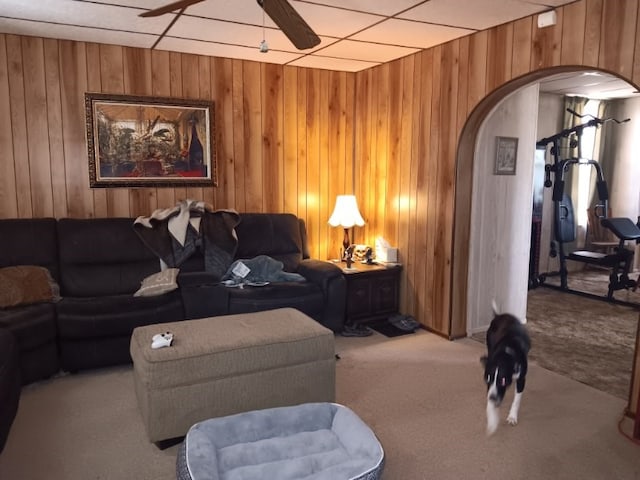 carpeted living room with wooden walls and ceiling fan