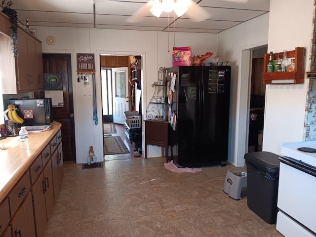 kitchen featuring white range with electric stovetop, black fridge, and ceiling fan