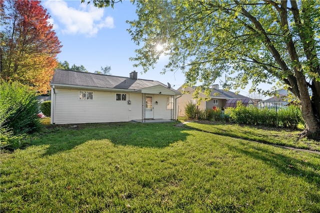 rear view of property featuring a lawn