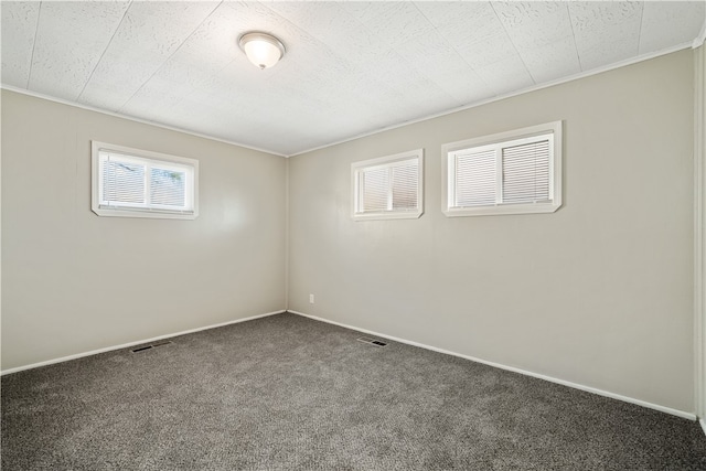 spare room featuring ornamental molding and dark carpet