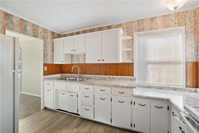 kitchen with white cabinets, sink, light wood-type flooring, crown molding, and white fridge