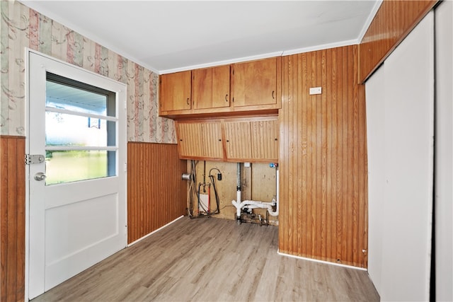 washroom with wood walls, light hardwood / wood-style floors, and ornamental molding