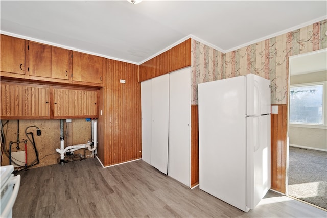 kitchen featuring crown molding, wooden walls, white refrigerator, and light hardwood / wood-style floors