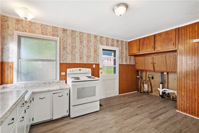 kitchen featuring white range with electric cooktop, light wood-type flooring, wood walls, and white cabinets