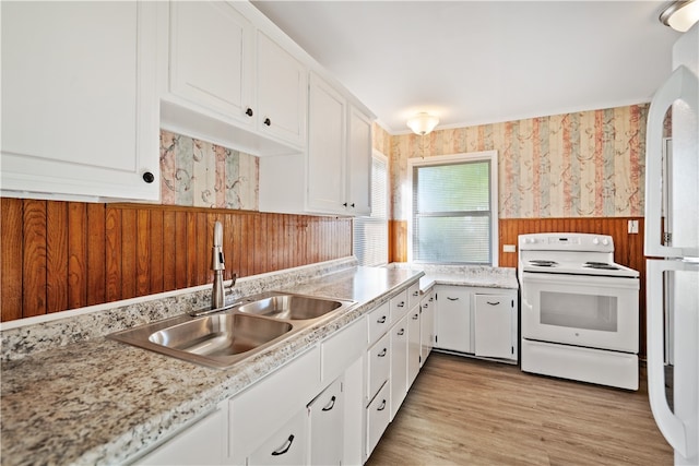 kitchen with wood walls, white range with electric cooktop, light wood-type flooring, sink, and white cabinetry