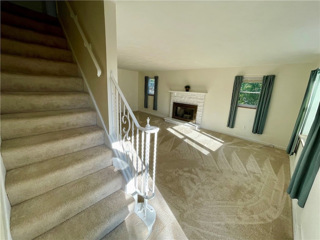 staircase featuring a stone fireplace and carpet