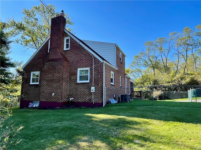 view of side of property featuring a lawn and central AC