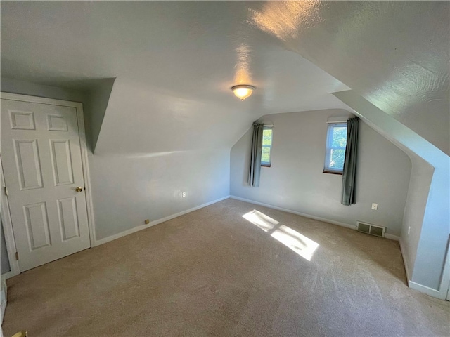 bonus room with light carpet, vaulted ceiling, and a textured ceiling