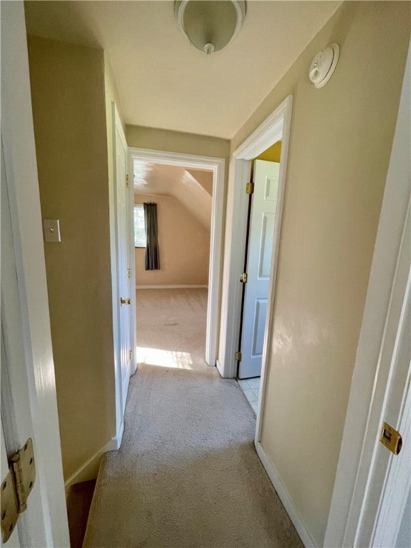 hallway with vaulted ceiling and light colored carpet