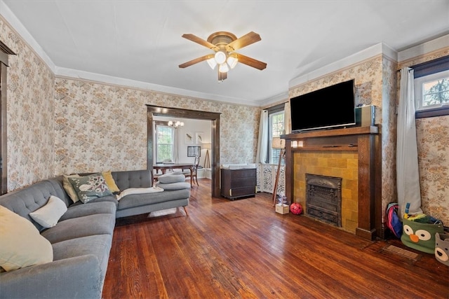 living room featuring a stone fireplace, dark wood-type flooring, and a healthy amount of sunlight