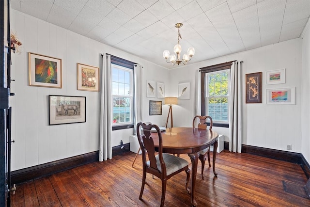 dining area with dark hardwood / wood-style floors and a notable chandelier