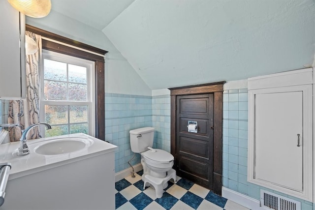 bathroom with lofted ceiling, vanity, tile walls, and toilet