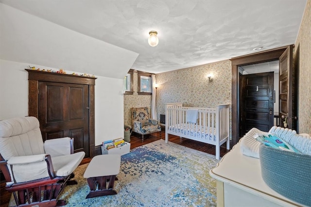 bedroom with a crib and hardwood / wood-style floors