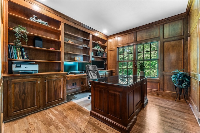 office with wood walls, built in desk, light hardwood / wood-style floors, and built in features