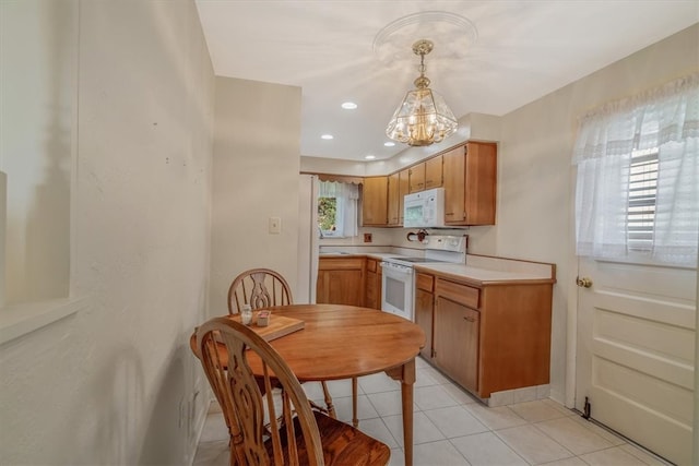 kitchen featuring light tile patterned floors, pendant lighting, white appliances, and an inviting chandelier