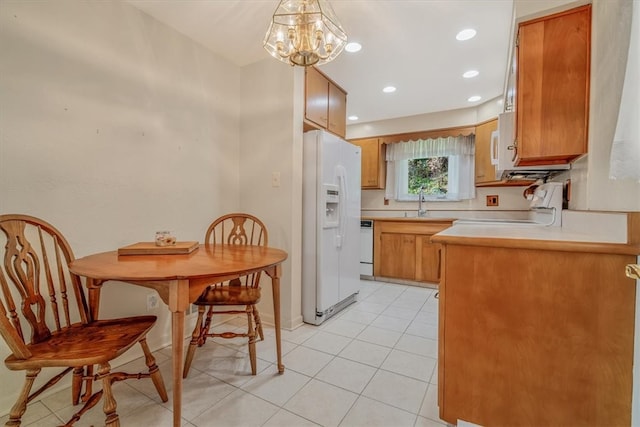 kitchen featuring pendant lighting, kitchen peninsula, light tile patterned floors, white appliances, and a notable chandelier