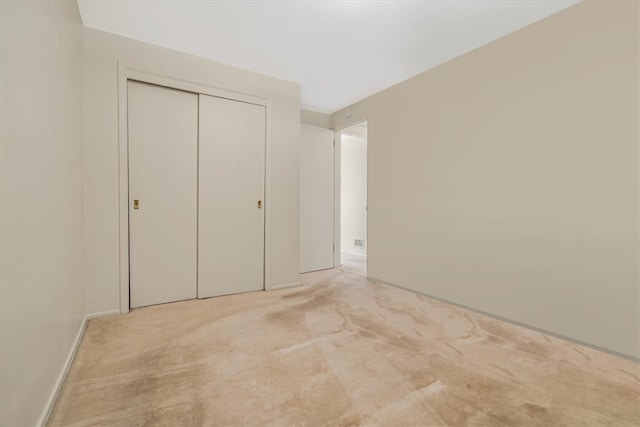 unfurnished bedroom featuring a closet and light colored carpet