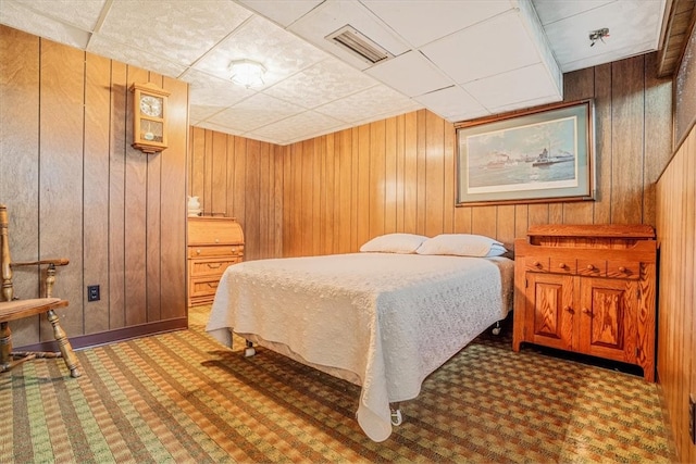 carpeted bedroom featuring wood walls