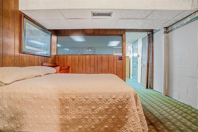 carpeted bedroom featuring wooden walls