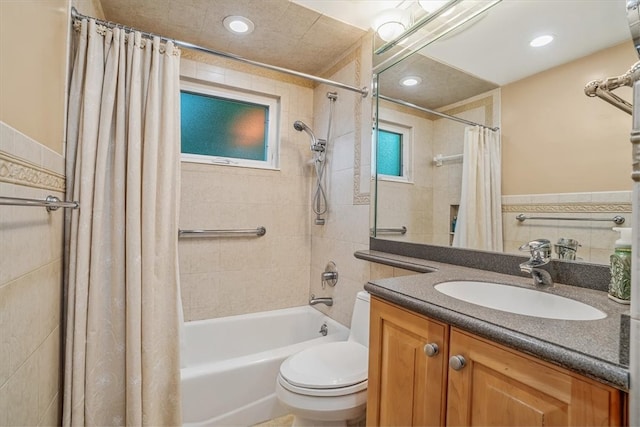 full bathroom featuring vanity, shower / bath combo with shower curtain, toilet, and tile walls