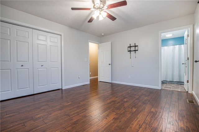 unfurnished bedroom featuring dark wood-type flooring, a textured ceiling, a closet, and ceiling fan