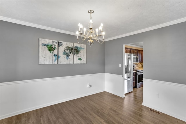 spare room with ornamental molding, dark wood-type flooring, a notable chandelier, and a textured ceiling