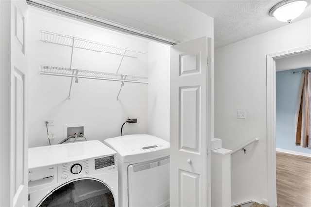 clothes washing area with a textured ceiling, wood-type flooring, and washing machine and dryer