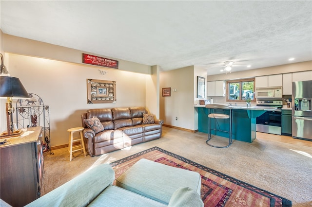 living room with light carpet, a textured ceiling, and ceiling fan