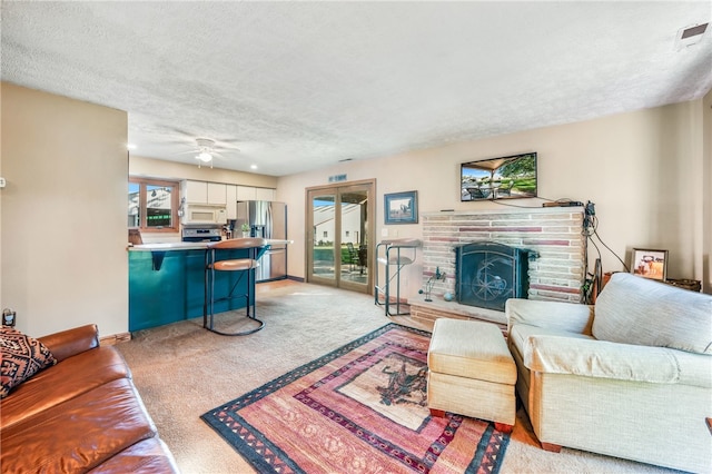 carpeted living room featuring a fireplace, ceiling fan, and a textured ceiling