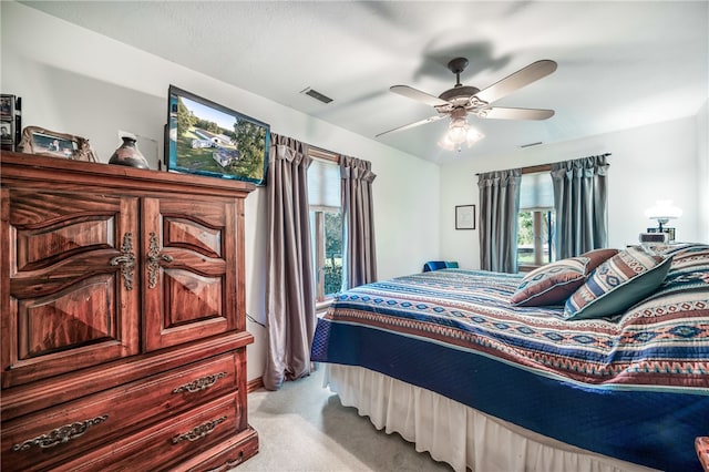 bedroom with ceiling fan, light colored carpet, and multiple windows