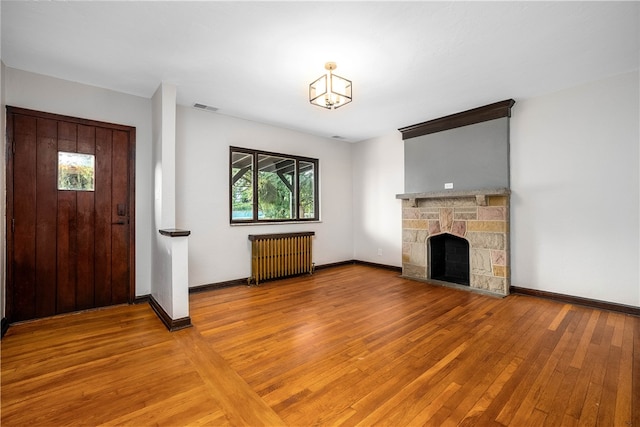 unfurnished living room featuring a fireplace, hardwood / wood-style floors, and radiator