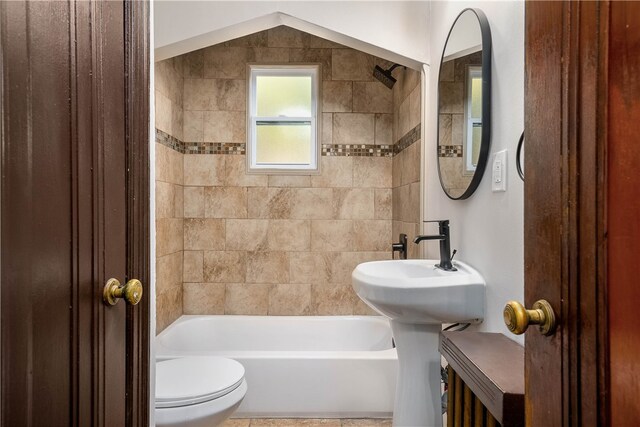 bathroom featuring lofted ceiling, tiled shower / bath, and toilet