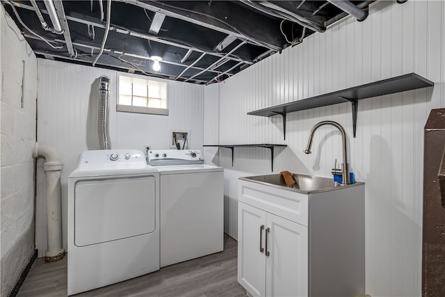 laundry room with wood walls, light hardwood / wood-style flooring, and washer and clothes dryer