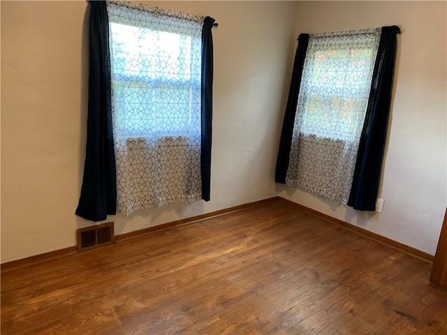 empty room with baseboards, visible vents, and wood finished floors