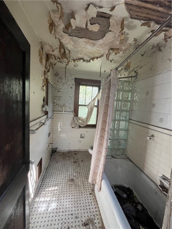 bathroom featuring toilet, tile walls, and  shower combination