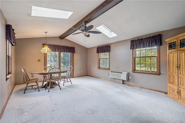 dining space featuring an AC wall unit, light carpet, a healthy amount of sunlight, and vaulted ceiling with skylight