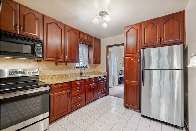 kitchen featuring tasteful backsplash, light stone counters, stainless steel appliances, light tile patterned floors, and sink