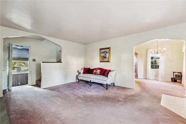 living area featuring ornamental molding, a healthy amount of sunlight, an inviting chandelier, and carpet