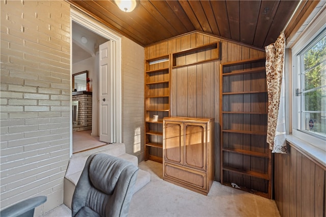 sitting room with lofted ceiling, wood ceiling, wooden walls, light carpet, and brick wall