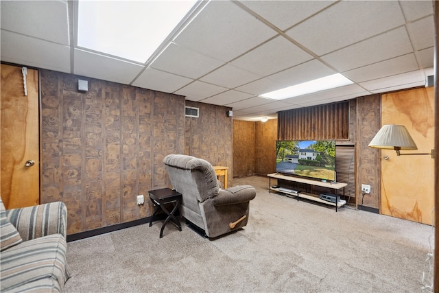 home theater room with wood walls, light colored carpet, and a paneled ceiling