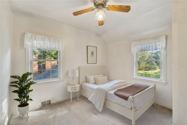 carpeted bedroom with ceiling fan, multiple windows, and lofted ceiling