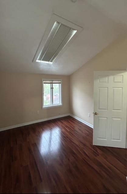 unfurnished room featuring vaulted ceiling and dark hardwood / wood-style floors